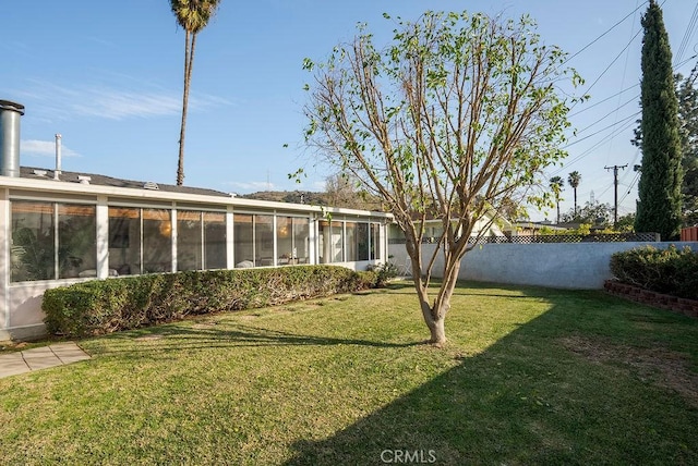 view of yard with a sunroom and fence