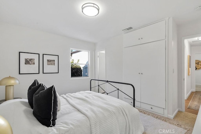 bedroom with baseboards, visible vents, a closet, and light colored carpet