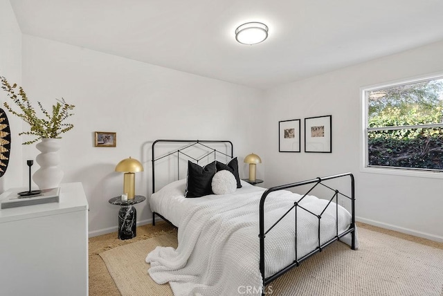 bedroom with light colored carpet and baseboards