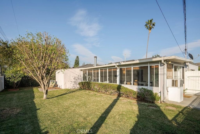 rear view of house with a sunroom, a yard, and fence