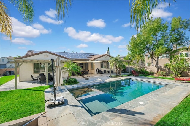 view of swimming pool featuring fence, a pool with connected hot tub, a lawn, a pergola, and a patio area