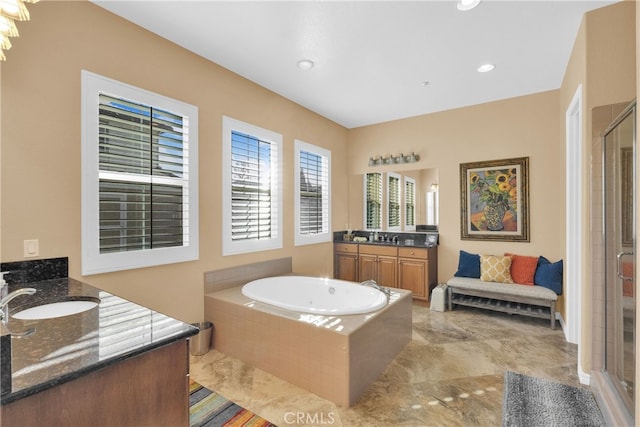 bathroom featuring a bath, a shower stall, two vanities, and a sink