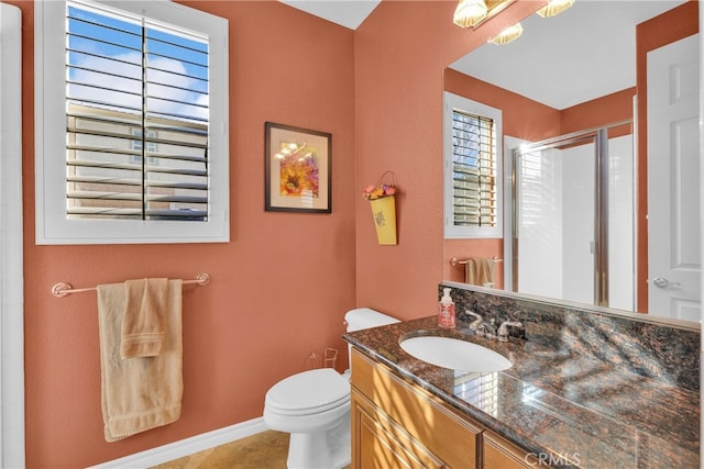 bathroom featuring a stall shower, baseboards, vanity, and toilet