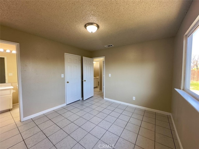 unfurnished bedroom featuring light tile patterned floors, baseboards, and visible vents