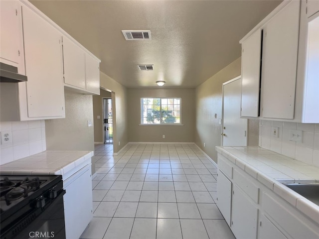 kitchen featuring tile counters, visible vents, and white cabinetry