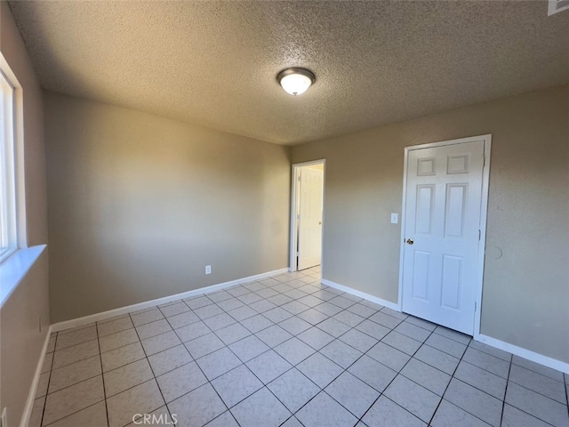 unfurnished room featuring a textured ceiling, baseboards, and light tile patterned floors