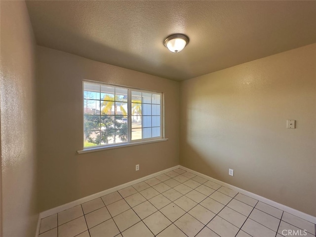 unfurnished room with a textured ceiling, baseboards, and light tile patterned floors