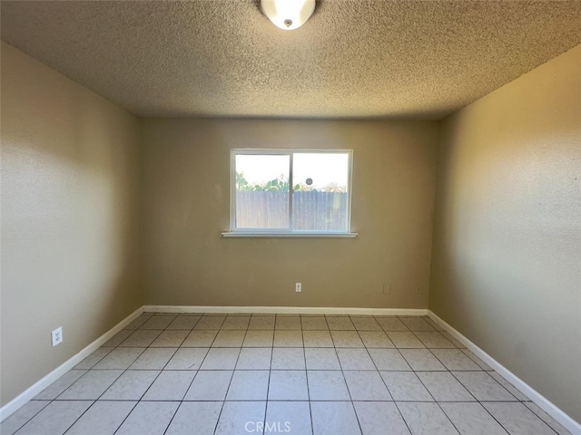 unfurnished room featuring a textured ceiling, baseboards, and light tile patterned floors