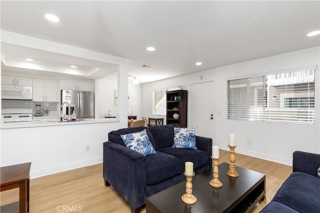 living area with recessed lighting, baseboards, visible vents, and light wood-type flooring