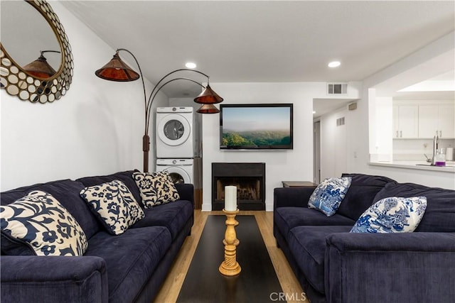 living area featuring stacked washing maching and dryer, recessed lighting, light wood-type flooring, and visible vents