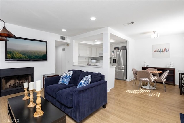 living area with light wood finished floors, a fireplace, visible vents, and recessed lighting