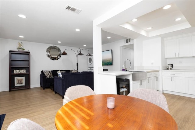 dining area with stacked washing maching and dryer, recessed lighting, light wood finished floors, and visible vents