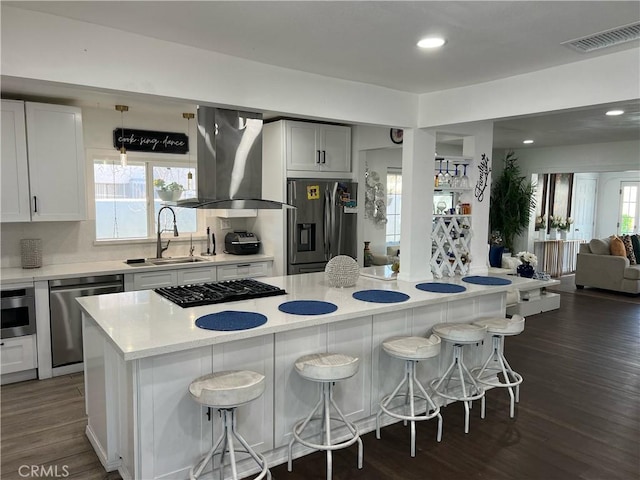 kitchen with visible vents, open floor plan, a kitchen breakfast bar, stainless steel appliances, and ventilation hood