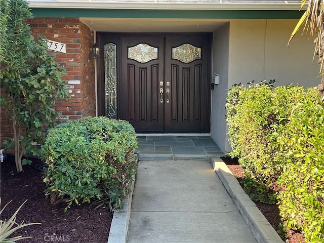 doorway to property featuring stucco siding and brick siding