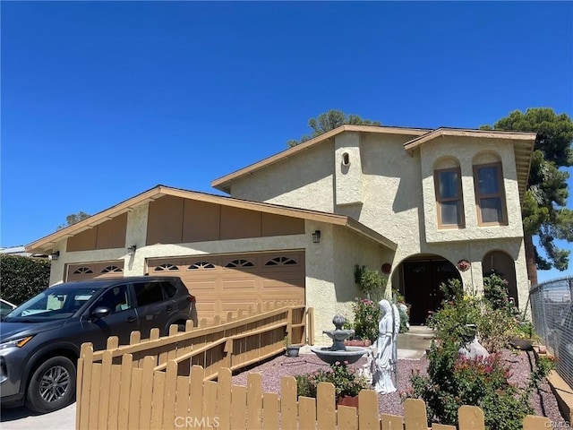 view of front of property featuring fence, an attached garage, and stucco siding