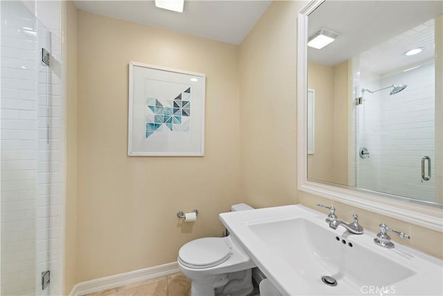 bathroom featuring toilet, a stall shower, a sink, baseboards, and tile patterned floors