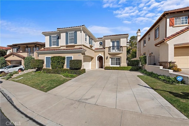 mediterranean / spanish-style home with a garage, concrete driveway, a tile roof, a front lawn, and stucco siding