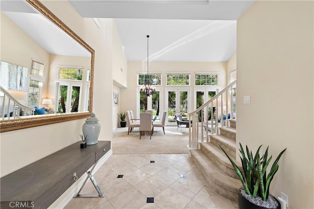 entryway with light colored carpet, an inviting chandelier, stairs, high vaulted ceiling, and light tile patterned flooring