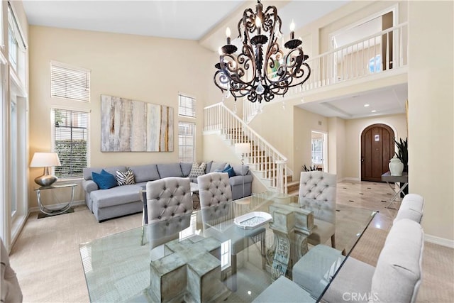 living area with arched walkways, a towering ceiling, an inviting chandelier, baseboards, and stairs