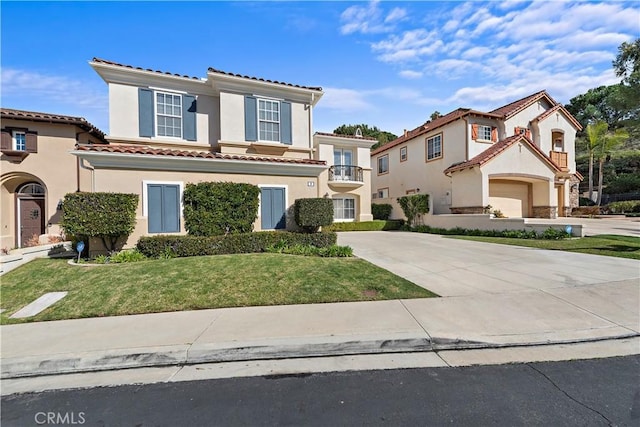 mediterranean / spanish-style house with driveway, a tiled roof, a front lawn, and stucco siding