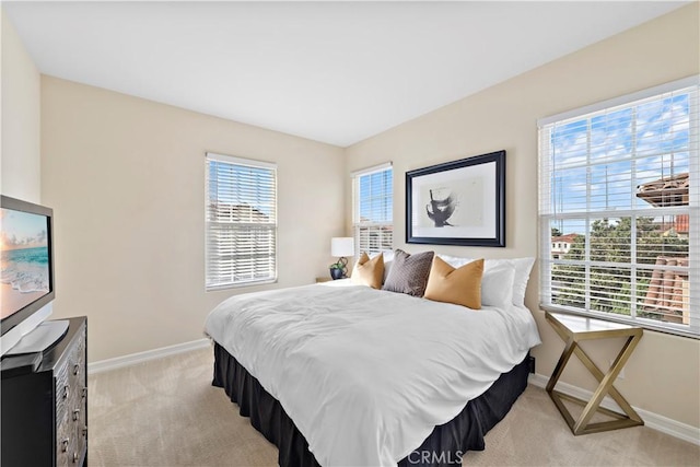 bedroom with light colored carpet, baseboards, and multiple windows