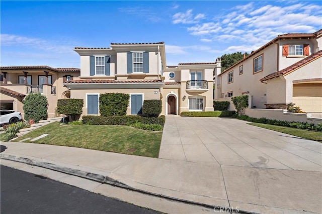 mediterranean / spanish-style house featuring driveway, a tiled roof, a residential view, stucco siding, and a front lawn