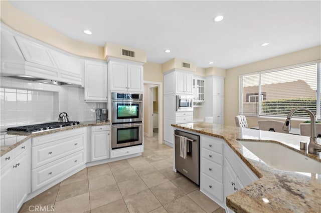 kitchen featuring visible vents, white cabinets, light stone counters, appliances with stainless steel finishes, and a sink