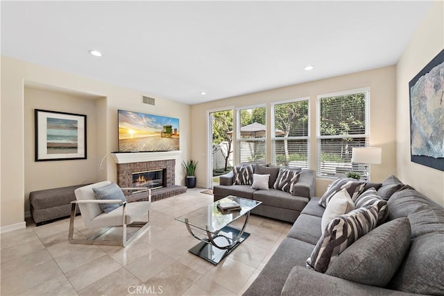 living area featuring a brick fireplace, baseboards, visible vents, and recessed lighting