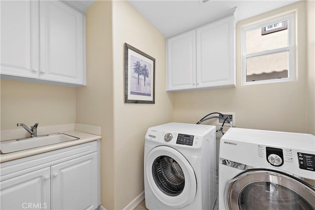 laundry area featuring washer and dryer, cabinet space, a sink, and baseboards