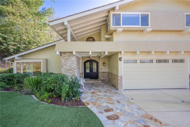 view of front of house featuring stone siding, french doors, driveway, and stucco siding