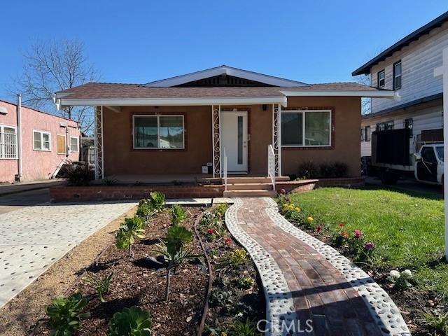 bungalow-style house with a front yard and stucco siding