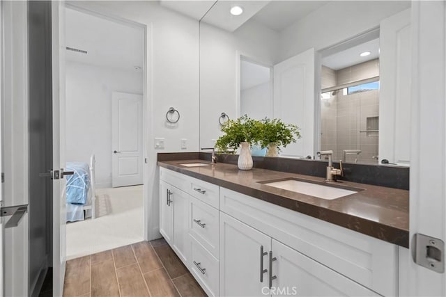 ensuite bathroom with ensuite bathroom, a sink, visible vents, a shower stall, and double vanity