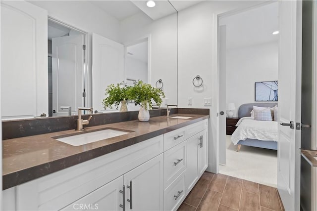 ensuite bathroom featuring double vanity, wood finish floors, ensuite bath, and a sink