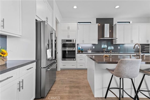 kitchen featuring wall chimney exhaust hood, white cabinetry, and stainless steel appliances