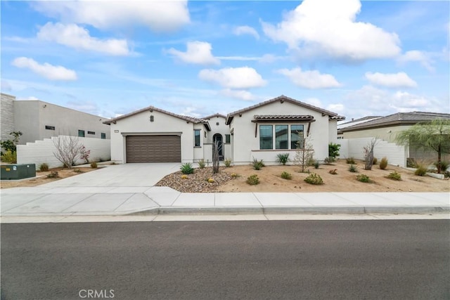 mediterranean / spanish-style home featuring an attached garage, fence, driveway, a tiled roof, and stucco siding