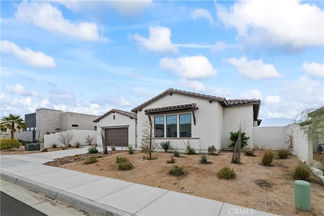 mediterranean / spanish home with a garage, concrete driveway, a tile roof, and stucco siding