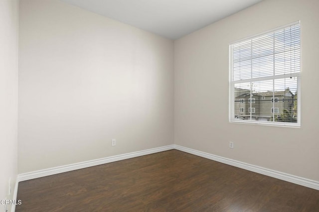 unfurnished room with baseboards and dark wood-type flooring