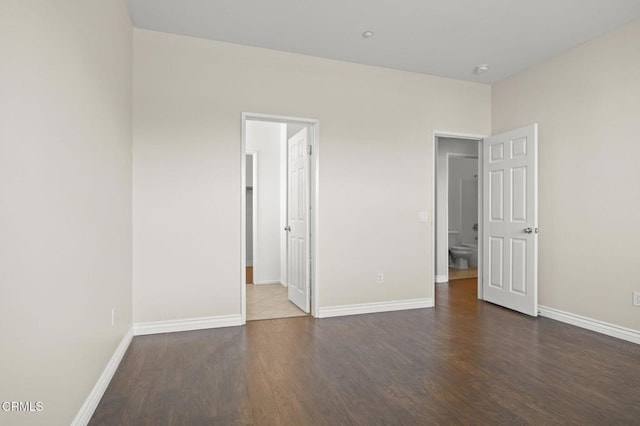 unfurnished bedroom with dark wood-type flooring and baseboards