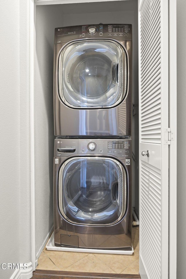 laundry room with laundry area, stacked washing maching and dryer, and tile patterned flooring