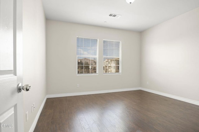 spare room featuring dark wood-style floors, baseboards, and visible vents