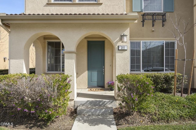 property entrance with a tile roof and stucco siding