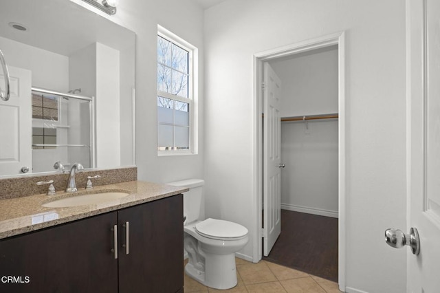 bathroom featuring a spacious closet, toilet, an enclosed shower, vanity, and tile patterned flooring