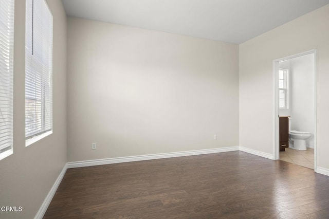 spare room featuring baseboards and dark wood finished floors