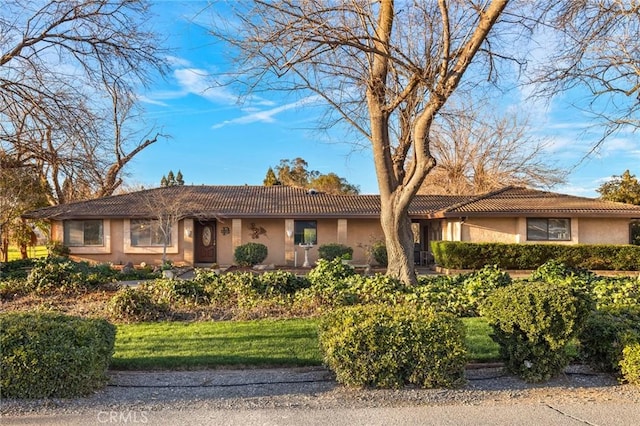 single story home with a tiled roof, a front lawn, and stucco siding