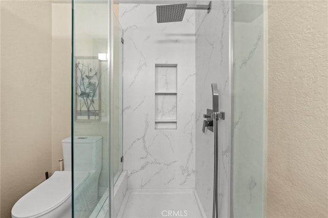 full bath featuring a marble finish shower, a textured wall, and toilet