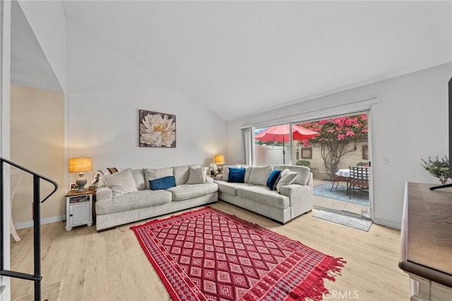 living room featuring baseboards, vaulted ceiling, and light wood finished floors