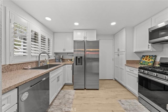 kitchen featuring appliances with stainless steel finishes, a sink, and white cabinets