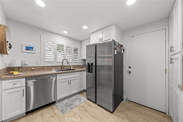 kitchen featuring white cabinets, light wood-style floors, stainless steel appliances, and a sink