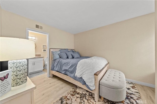 bedroom featuring light wood-style floors, visible vents, baseboards, and ensuite bathroom