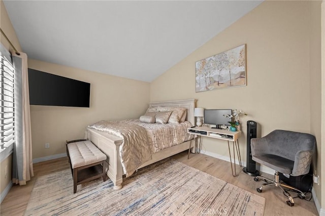 bedroom with lofted ceiling, light wood-style flooring, and baseboards